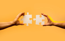 Closeup Hand Of Connecting Jigsaw Puzzle. Business Solutions, Success And Strategy Concept. Two Hands Trying To Connect Couple Puzzle Piece On Yellow Background. Holding Puzzle. Teamwork Concept