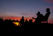 Silhouette Of A Family Toasting Marshmallows Around A Fire Pit, USA