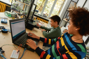 To create and invest is time well spent. Students building and learning to program robot vehicle at a stem robotics class. Science and education.