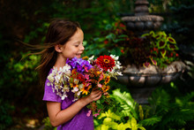 A Young Girl Outdoors With A Bouquet Of Flowers