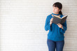 © N_studio - Beautiful asian woman smiling standing thinking and writing notebook on concrete cement white background at home, girl homework on book, education and lifestyle concept.