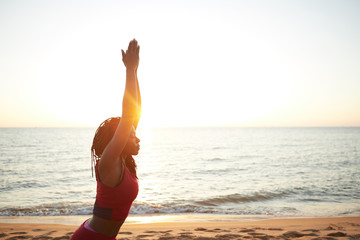 Wall Mural - Fit young woman standing in morning sun rays and practicing warrior pose