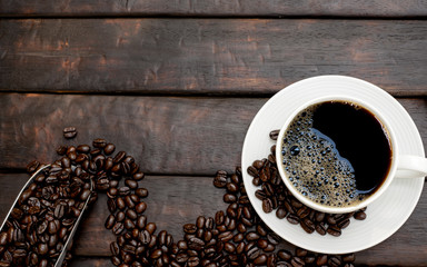 Poster - black coffee with beautiful froth in a classic coffee cup with roasted coffee beans and a coffee scoop top view