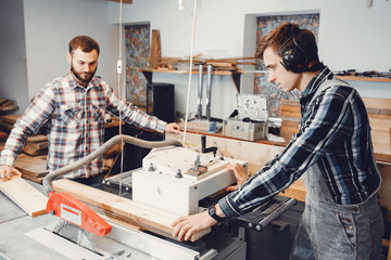 Wall Mural - Two men carves a tree. The carpenters works in a studio. An engineer provides a tree shape