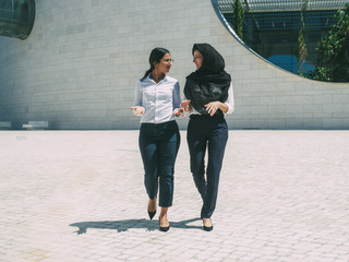 multicultural female business colleagues discussing project outside. women wearing office clothes an