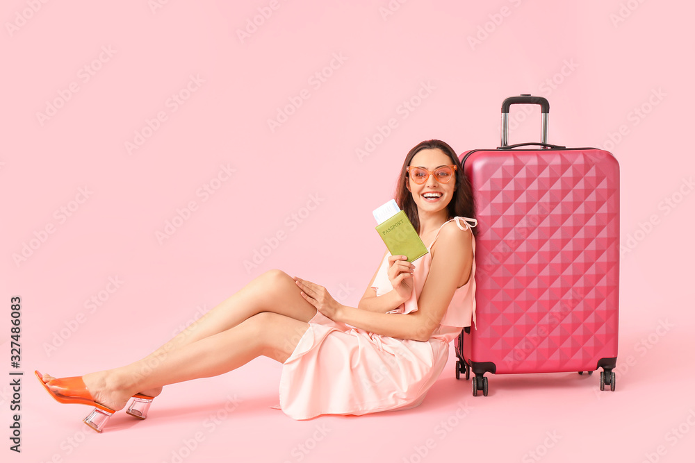 Female tourist with documents and luggage on color background