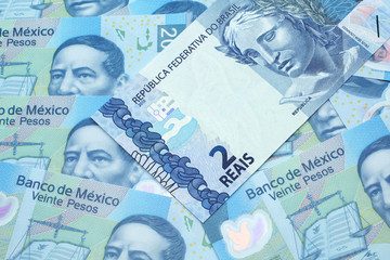 A blue two reais bank note from Brazil close up in macro with a background of United States Mexican twenty peso bills