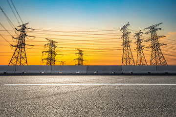 Canvas Print - Electricity tower silhouette and empty asphalt road at dusk