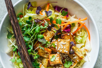 Wall Mural - Fried tofu salad with sprouts and sesame seeds in white bowl, top view. Vegan food, asian food concept.