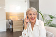 © Graphicroyalty - Happy senior woman using mobile phone at home. Smiling cool old woman with white hair sitting on sofa and messaging with smartphone. Beautiful stylish elderly lady talking on cellphone.