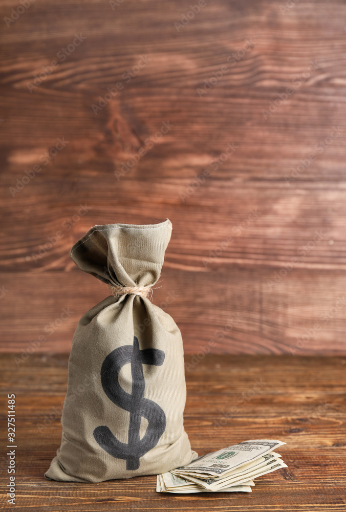 Bag with money and dollar banknotes on wooden background