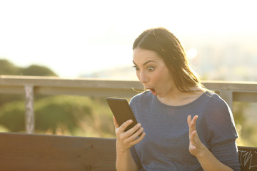 Poster - Surprised woman looking at her phone on a park