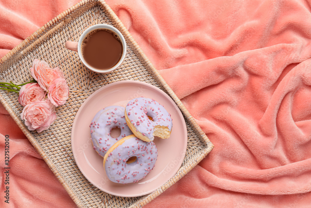 Tray with tasty donuts and cup of coffee on bed