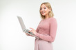 © Ivan Traimak - charming blonde girl is typing on a laptop keyboard while holding in her hands on a white studio background