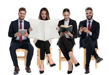 Poster - Four businessmen reading from book, newspaper, phone and tablet