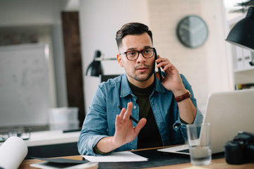 Businessman in office. Handsome man talking on phone at work.