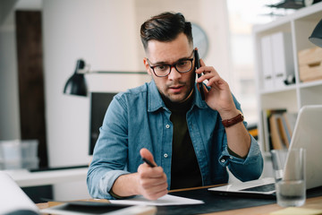 businessman in office. handsome man talking on phone at work.