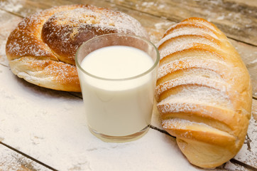 glass of milk, loaf, on a wooden background with flour. Balanced diet, protein and carbohydrates, cereals