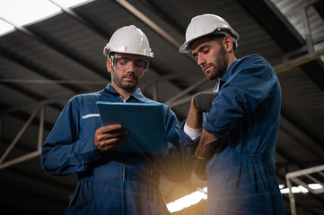 Wall Mural - Factory technicians are discussing or planning work. They wear uniforms, safety helmets, and protective goggles. And look at the clipboard with details of the work.