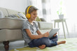 © New Africa - Cute little boy with headphones and tablet listening to audiobook at home