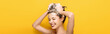 panoramic shot of happy girl with closed eyes washing hair on yellow background