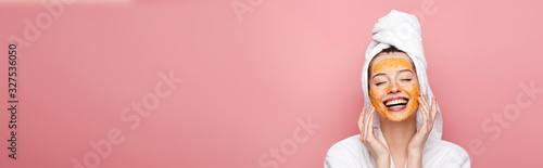Fotomural panoramic shot of happy girl with citrus facial mask touching face with closed e