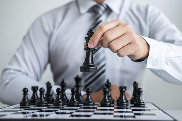 Black and White chess with player, Hands of businessman thinking to moving chess figure in competition and planning strategy to success play for win