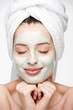 © LIGHTFIELD STUDIOS - smiling girl with facial nourishing mask and towel on head holding hands near face isolated on white