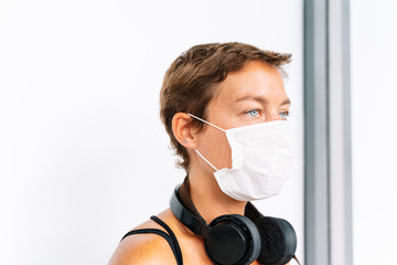 portrait of a young caucasian girl with headphones and a medical mask