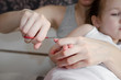© silentalex88 - mother cuts her daughter's nails with scissors in the bedroom - focus on her hands. baby hygiene