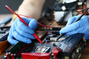 Hands are repairing an electronic device, soldering. Service center for computer repair. Restoration soldering power elements circuit, diagnostics state capacitors. Repair components any complexity