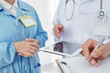 © DragonImages - Cropped image of doctors reading list of symptoms on tablet computer and making diagnosis together