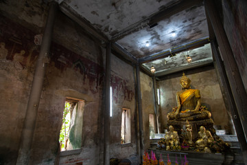 Wall Mural - Ancient golden buddha statue in church, ancient temple is Wat Bang Kung, outside is covered with root of banyan tree.