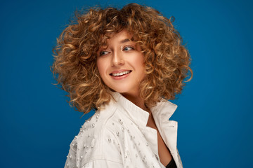 Wall Mural - Portrait of pretty blonde woman with curls isolated on blue background