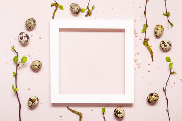 Wall Mural - White Frame with quail eggs and blooming twigs over pink pastel background. Happy easter natural concept