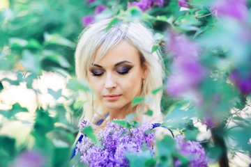 portrait of a beautiful girl in close-up in lilac flowers. Professional makeup in lilac tones.