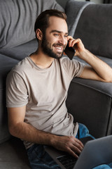 Poster - Pleased young man talking by mobile phone.