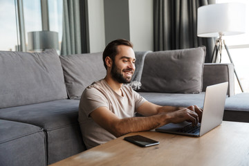 Wall Mural - Optimistic young man indoors using laptop computer.