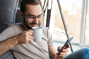 Poster - Optimistic young man indoors drinking coffee