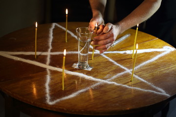 Wall Mural - Men's hands set candles on the pentagram symbol