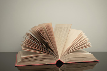 Poster - Close up beautiful open book on a gray and glass table background.
