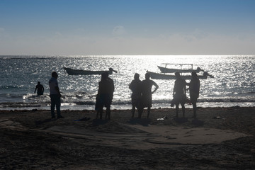 a sporty friends group on the beach about to go swimming.  Silhouette people group on the beach at Tulum