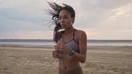 Wall Mural - A good-looking young african american woman in sportswear is doing exercises on the beach in the morning