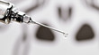 eine Injektionsnadel aus der Impfstoff tropft in dem sich ein Totenkopf Symbol spiegelt
