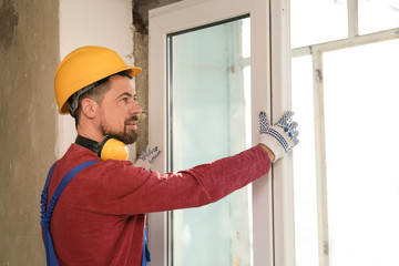 Sticker - Worker in uniform installing plastic window indoors