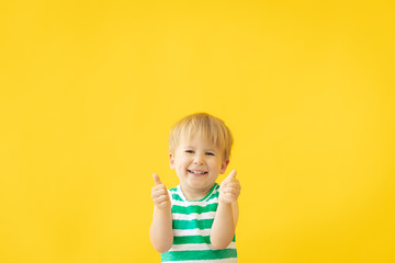 Wall Mural - Portrait of happy child against yellow background. Summer vacation concept