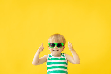 Wall Mural - Portrait of happy child against yellow background. Summer vacation concept