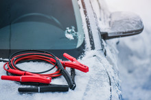 Charging Cars Battery With Electricity Trough Electric Cables. Vehicle Jumper Cable On Car Need Starting Or Connection In Winter Time.