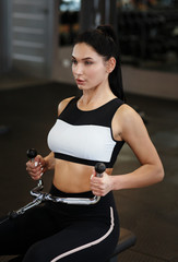 Wall Mural - Pretty woman exercising with cable weight machine in sports club