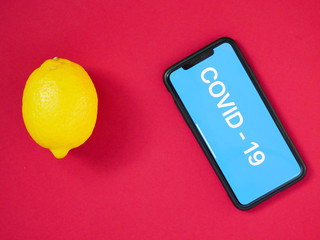 lemon and smartphone with the inscription COVID - 19 on a colored background. Vitamin C. The concept of treatment of the virus